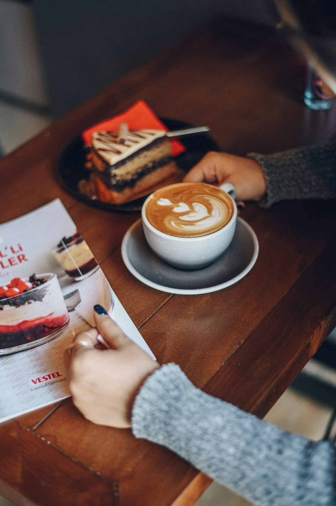 Hands writing notes in a notebook next to a coffee cup
