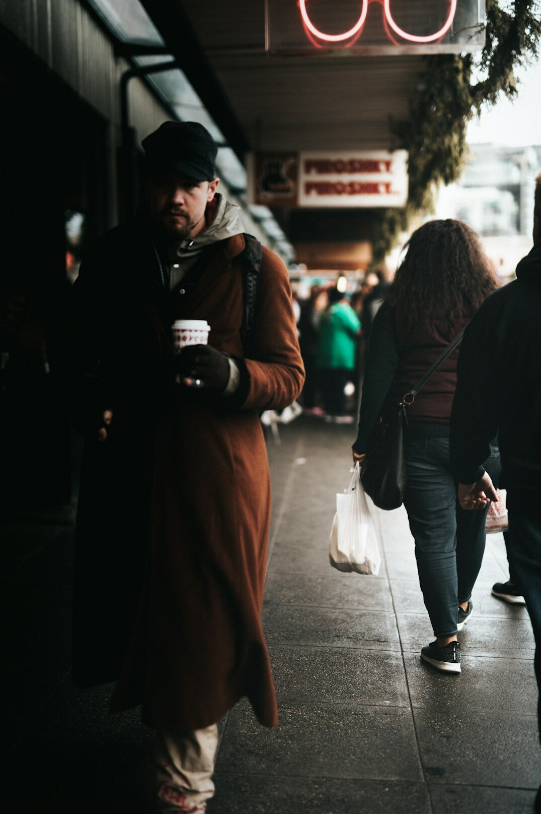 Young man waiting in line holding a coffee cup